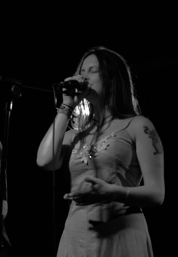 Black and white photo of Silvia Leonzio standing singing with a microphone in her hand